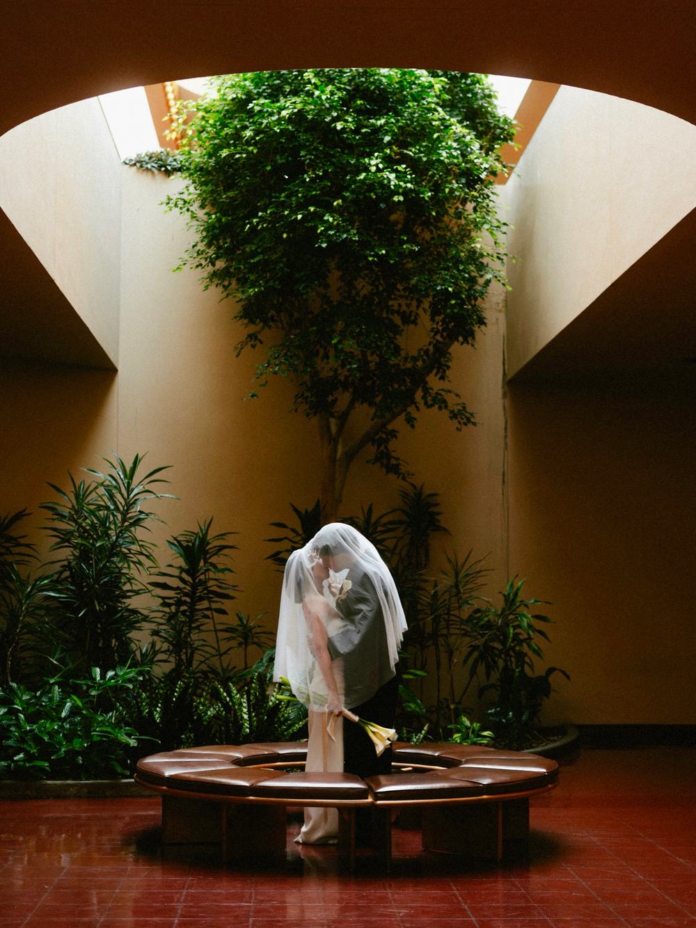 A newly married couple standing beneath a veil in a quiet interior courtyard